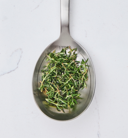 One tablespoon of fresh thyme leaves on stainless steel measuring spoon